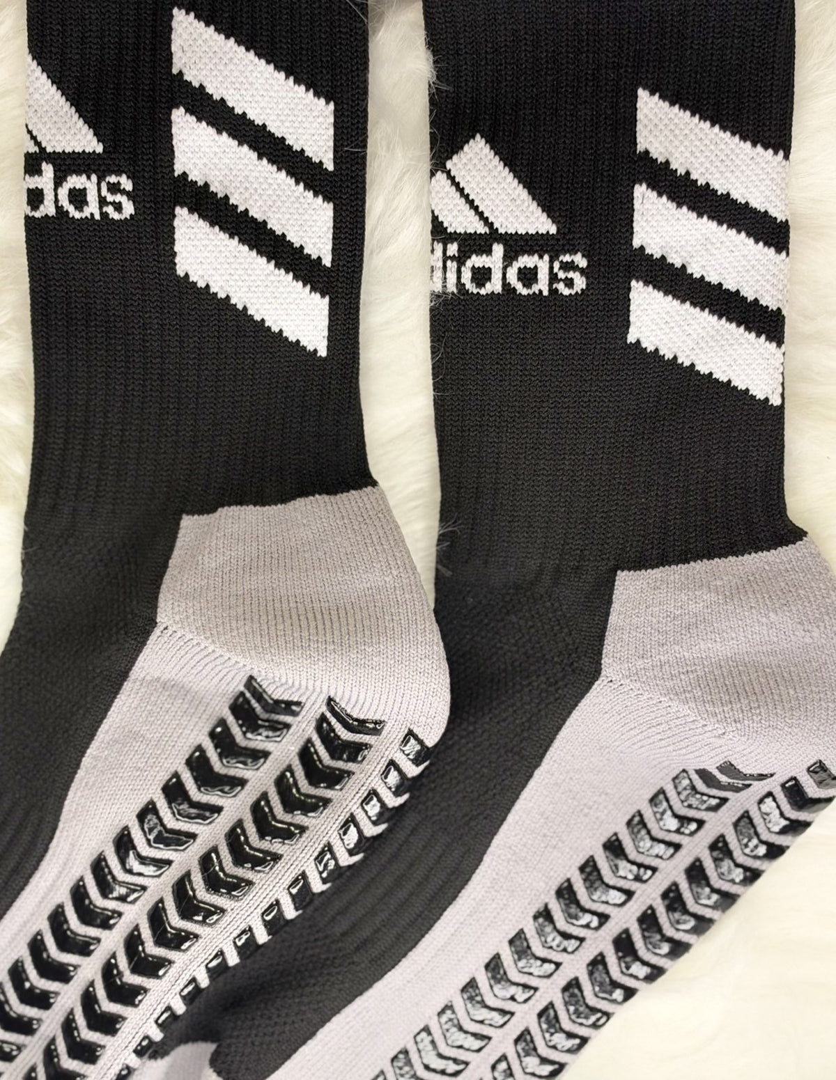Close-up of white stripes and rubber grip pads on black football socks