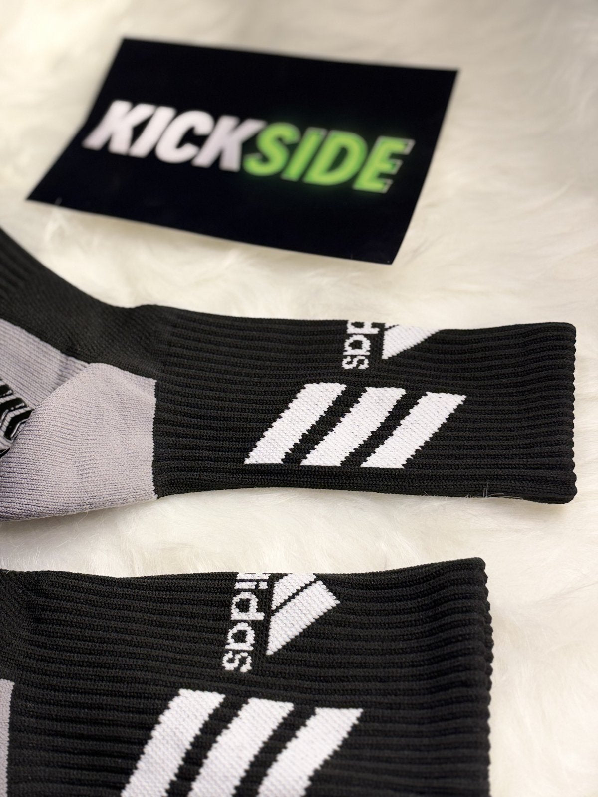 Close-up of the ribbed cuff and stripes on black football grip socks